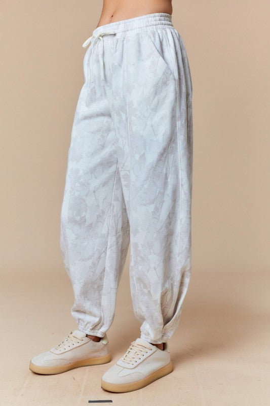 Pantalones deportivos color beige desteñido con estampado de hojas